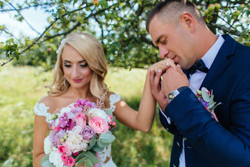 Stunning wedding couple poses on the summer field with tall grass