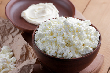 Cheese, cottage cheese and cream in clay pots, fresh cottage cheese on a wooden background, sour cream in rustic style, healthy food, French breakfast, top view, goat curd on parchment paper, protein