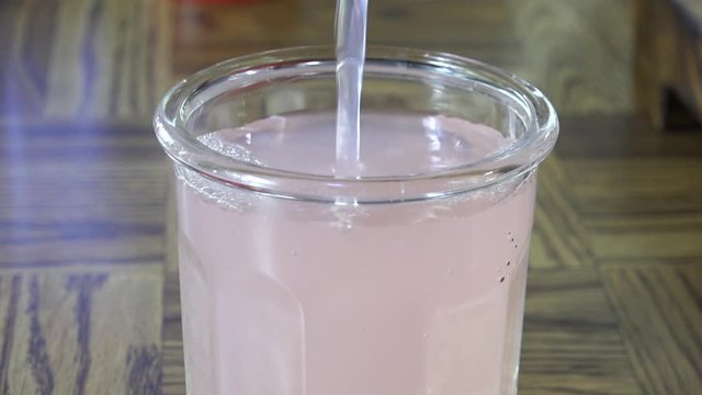 Pouring pink lemonade into a glass slow motion
