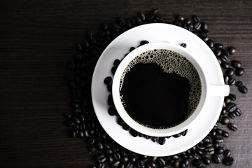 Black coffee in white cup and coffee bean on wood table background.