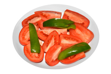 Slices of tomatoes and green pepper on plate isolated on white background