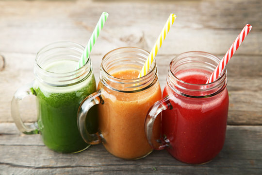 Sweet smoothie in glass jars on grey wooden table