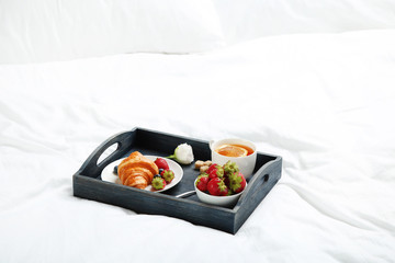 Tasty breakfast in bed on wooden tray