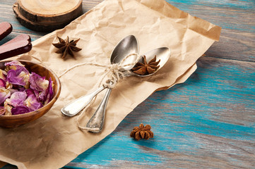 Vintage tea spoons and rose petals on wooden blue background