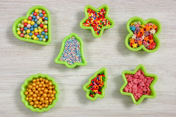 Multicolored candy in baking molds. Sugar powder for a cake on a white wooden table. View from above.