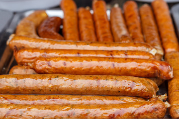 Fresh, hot sausages cooked on the grill, outdoors, on the coals.