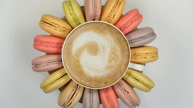 Pastel macarons around a coffee cup