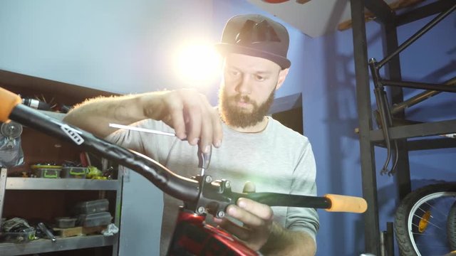 A young male mechanic in his workshop assembles a bicycle