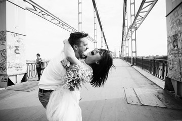 The lovely couple in love embracing on the bridge