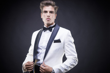 Obraz premium Business Stylish Luxury, elegant man in a white suit tuxedo with bow tie around his neck
