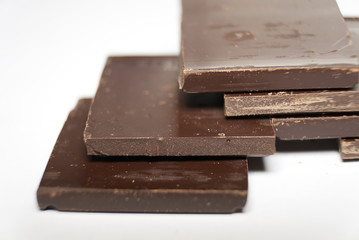 Pieces of dark chocolate on white background. Macro