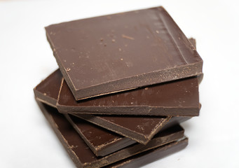Pieces of dark chocolate on white background. Macro