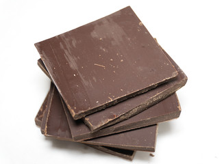 Pieces of dark chocolate on white background. Macro