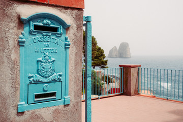 Vintage post box with Faraglioni on the background.
