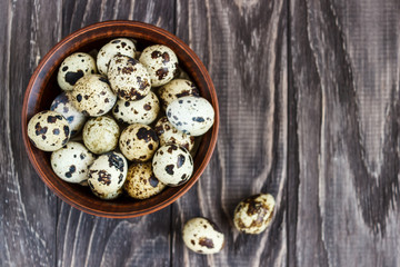Quail eggs in a clay plate on a wooden background, a plate for storing quail eggs, a symbol of the Easter season. Healthy eating.