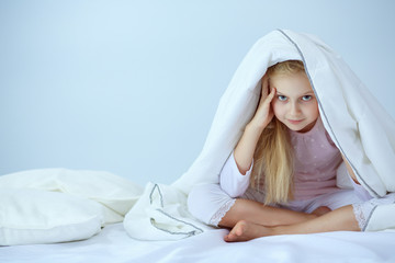 Smiling little girl in the bed under cover