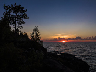 The sun setting behind a cloud bank reflecting on a lake