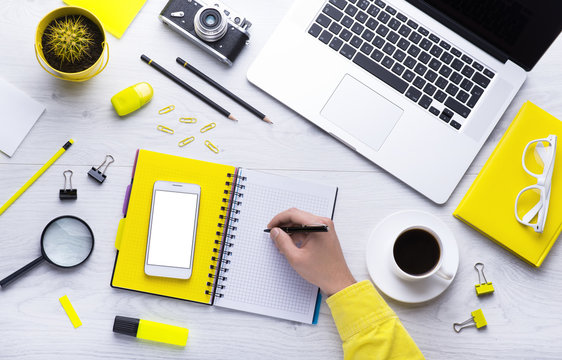 Workplace with office tools and gadgets. Cup of coffee on a table. Tablet, laptop, phone and camera to develop applications or other projects. White, black and yellow background. Flat layer photo.