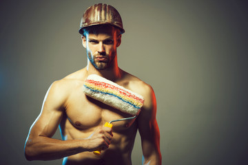Room painting job. Room painter with painting roller. Young painter contractor in helmet. Confident...