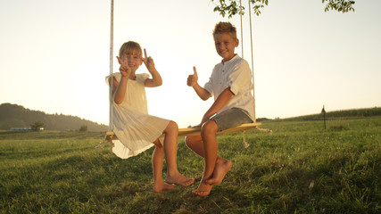 Joung boy and girl swinging on a swing