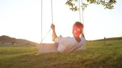 Fototapeta premium Joung boy swinging on a swing
