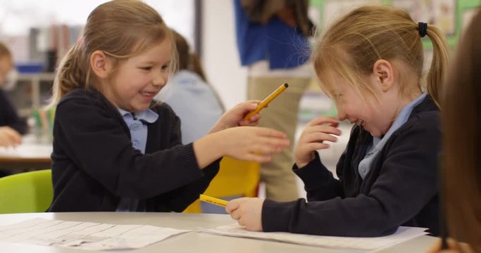 4K Cute little girls playing & tickling each other in school classroom. Slow motion