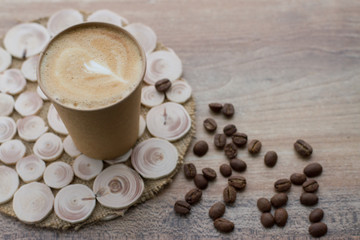 Coffee to go in paper cup on wooden background with coffee beans, place for text