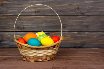 Easter eggs in the basket on wooden background.