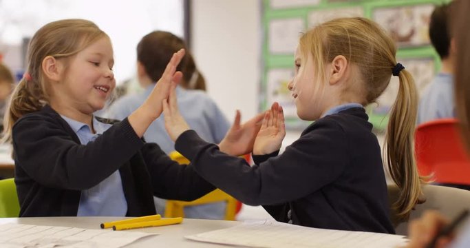 4K Cute little girls playing pat-a-cake together in school classroom. Slow motion