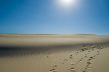 Sand dunes with blue sky and sun