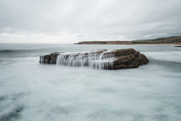 A sea stack in the Pacific Ocean takes on a huge wave