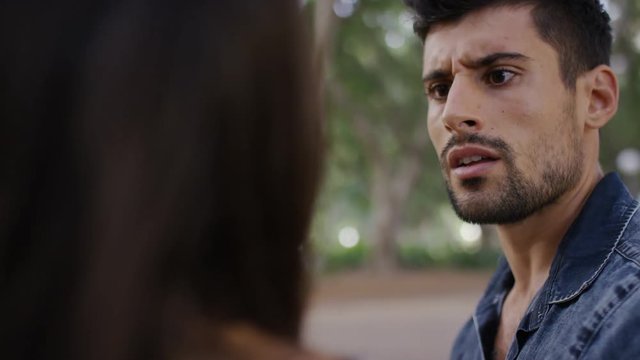 Young man having an argument with his girlfriend outdoors in a park