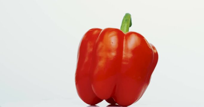 Macro shooting of the spinning red pepper on the white wall background. Close up