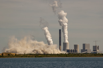 Factory chimney being torn down by explosion. Huge dust cloud immediately after explosion.