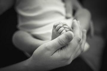little newborn baby feet in mom's suppoting hands
