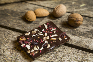 Pieces of black, chocolate with cranberry , nuts and almond  on wood background