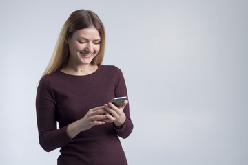 Naklejka premium A girl in a burgundy dress on a gray background reads a sweet sms