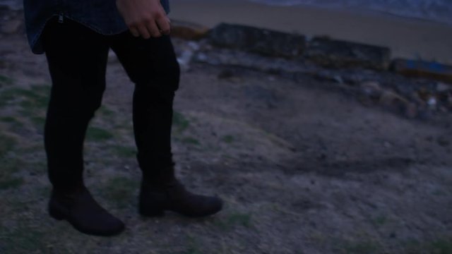 Handsome man walks along the coast and throws a stone into the water
