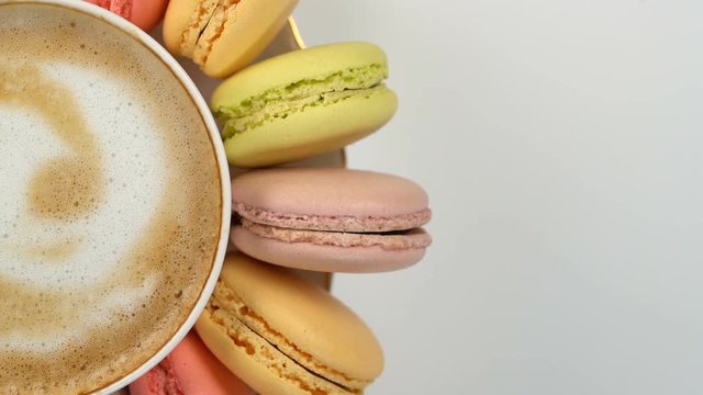Pastel macarons around a coffee cup