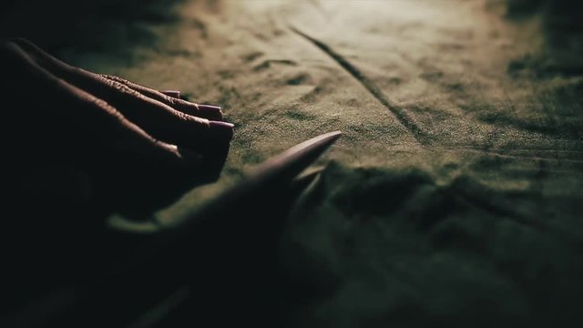 Tailor cutting fabric using large scissors or shears as he follows the chalk markings of the pattern, close up of his hands