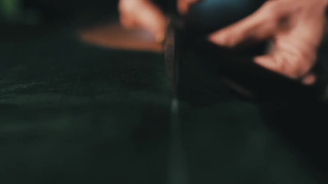 Tailor cutting fabric using large scissors or shears as he follows the chalk markings of the pattern, close up of his hands