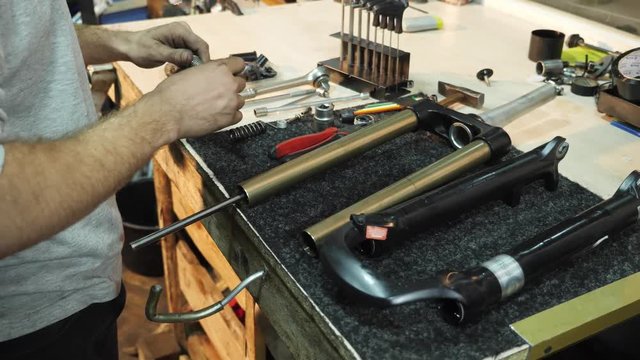 The mechanic uses a hammer to repair a bicycle