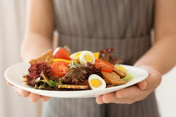 Obraz na płótnie Canvas Woman holding salad with quail eggs and tomatoes on white plate
