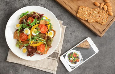 Composition with fresh salad and smartphone on grey table