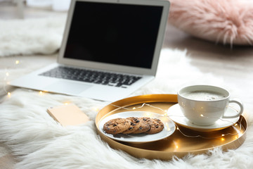 Laptop, mobile phone and tray with tasty breakfast on fluffy carpet