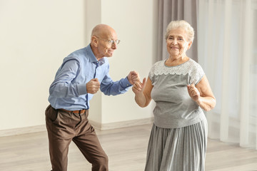Cute elderly couple dancing at home