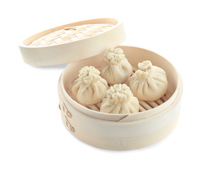 Tasty baozi dumplings in bamboo steamer on white background