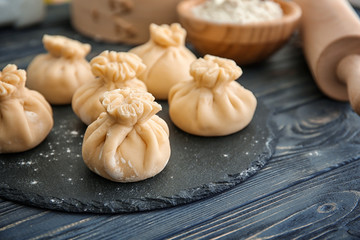 Obraz na płótnie Canvas Slate plate with tasty baozi dumplings on table