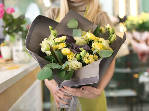 Female florist holding beautiful bouquet in flower shop