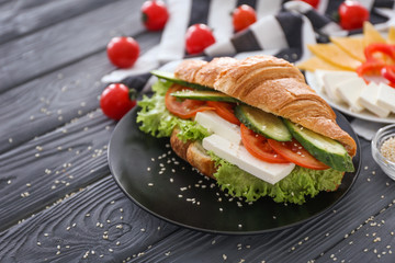Plate with tasty croissant sandwich on table